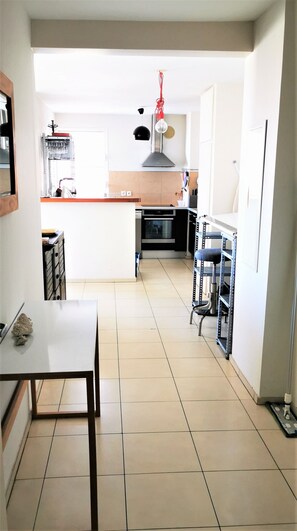 A modern kitchen with a central island, a dining table, and a built-in oven. - Appt "Longanis" St-Gilles Les Bains - T3 pleasant and quiet sea view - 4 pers (Saint-Gilles les Bains)