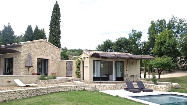 A stone house with a swimming pool, outdoor seating, and a garden.