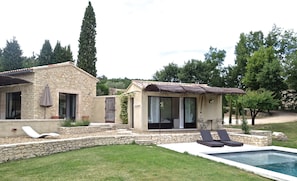 A stone house with a swimming pool, outdoor seating, and a garden.