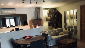 A modern kitchen with a dining area, a sofa, and a bookshelf. - Large salted swimming pool heated from May to September for 4 people (Vence)