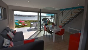 A modern living room with a large sliding glass door leading to a patio area with outdoor furniture.