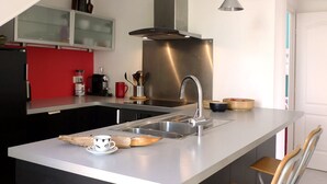 Une cuisine moderne dotée d’un îlot central, d’appareils électroménagers en acier inoxydable et d’un pare-feu rouge.