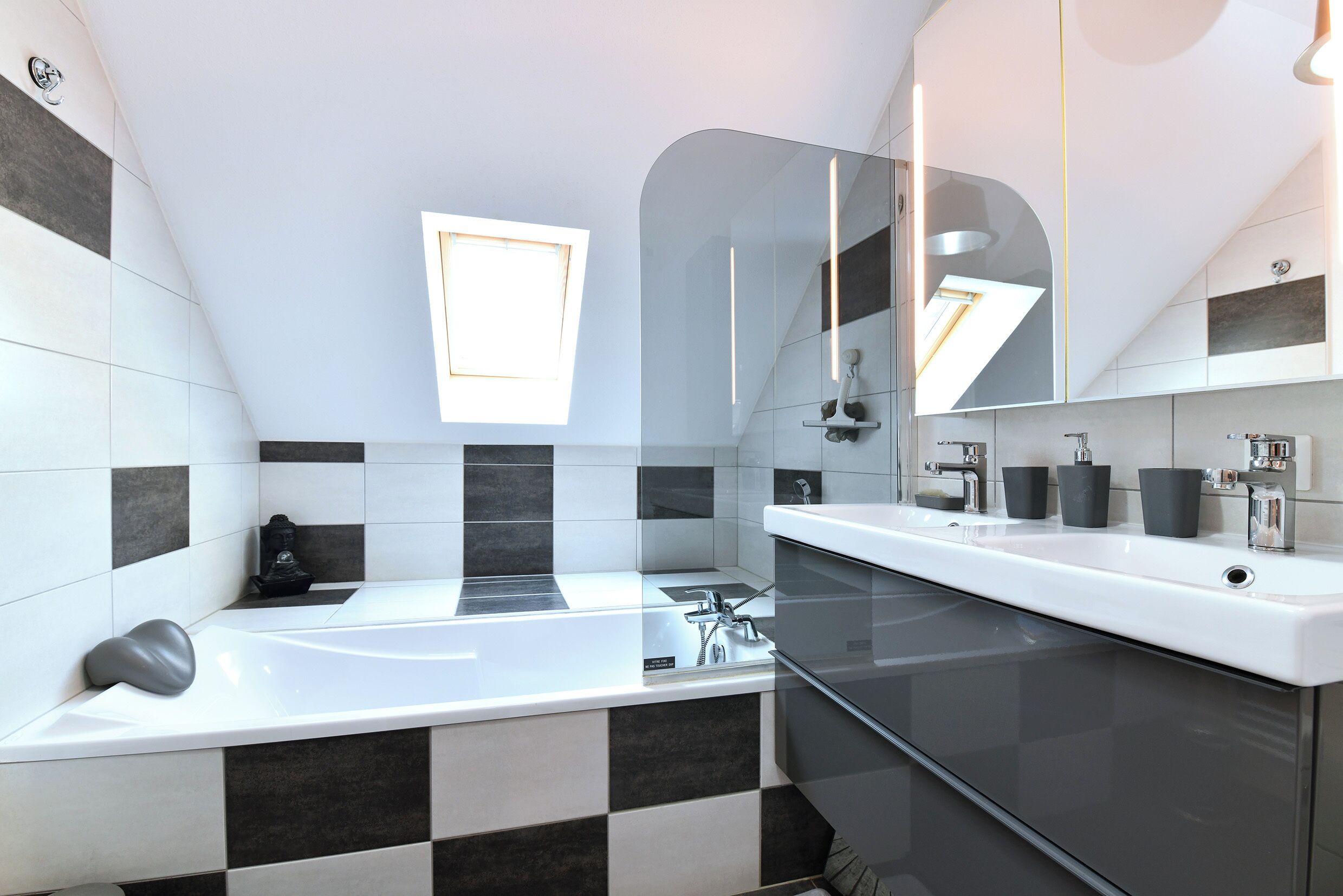 A modern bathroom with a bathtub, two sinks, and a large mirror.