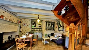 Ein gemütlicher, rustikaler Raum mit Holzböden, einem Esstisch mit Stühlen, einer Couch und einer Treppe.