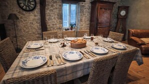 A dining room with a checkered tablecloth, wicker chairs, and a stone wall.