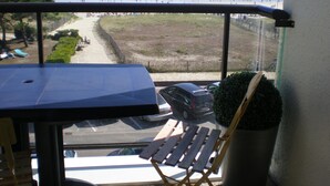 A balcony with a view of the beach and ocean. There is a chair and a table on the balcony. - view apartment stunning sea views (Carnac)