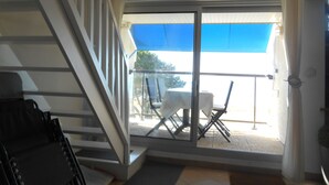 A room with a staircase, a balcony with a table and chairs, and a view of the outside. - view apartment stunning sea views (Carnac)