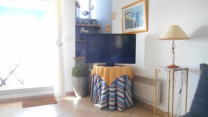 A living room with a television, a potted plant, a striped sofa, and a lamp. - view apartment stunning sea views (Carnac)