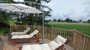A wooden deck with two lounge chairs and a large umbrella. - Perigordian style property (Saint-Pierre-d'Eyraud)