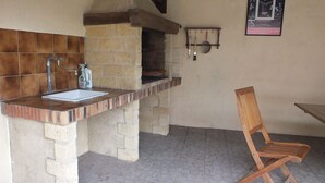 A kitchen with a brick oven, a sink, and a wooden chair. - Perigordian style property (Saint-Pierre-d'Eyraud)