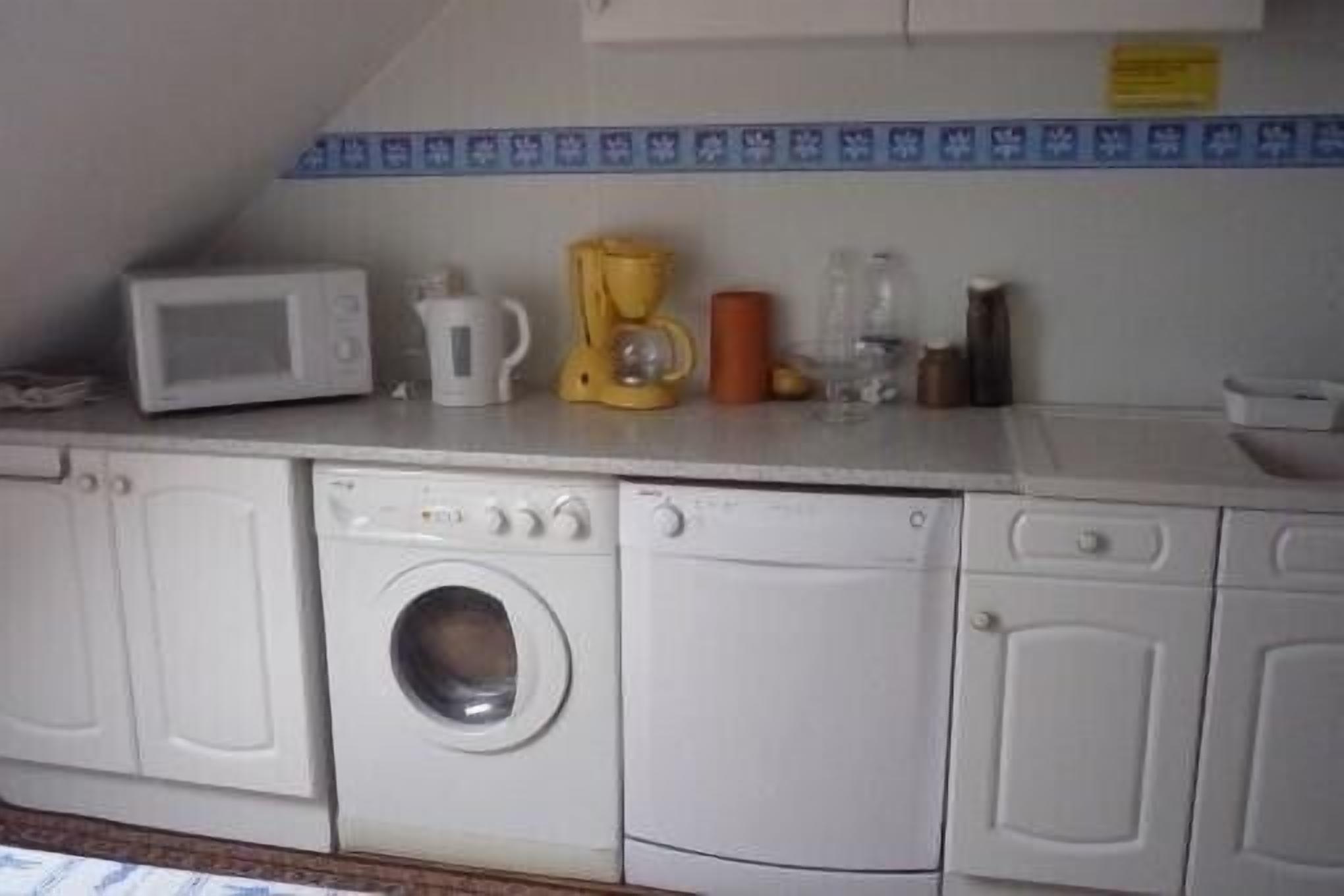 A laundry area with a washing machine, dryer, microwave, and coffee maker.