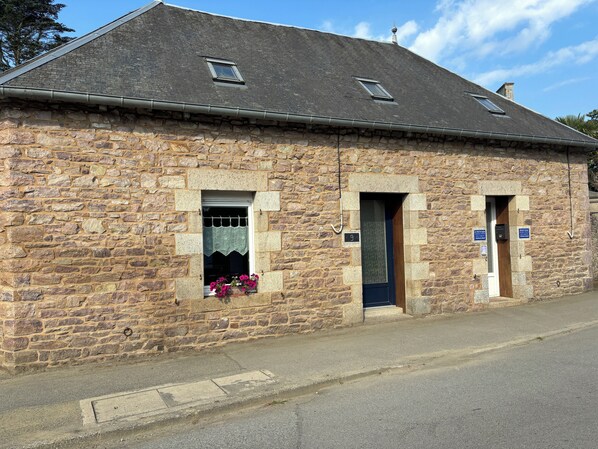 A stone building with two doors and a window with flowers.