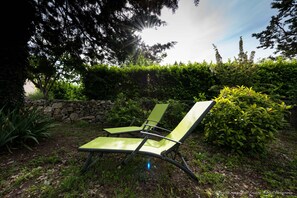A green lounge chair in a garden with a stone wall and dense foliage in the background. - cottage in southern Ardèche with swimming pool (4 X 8) on large enclosed land (4000m) (Saint-Maurice-D'ibie)