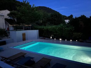 A rectangular swimming pool with a clear blue water surface, surrounded by a white wall and a wooden deck with lounge chairs. - House on the hills of Provence overlooking vineyards ... (Séguret)