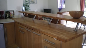 Una cocina con encimera de madera, un lavamanos, armarios y una ventana con cortinas.