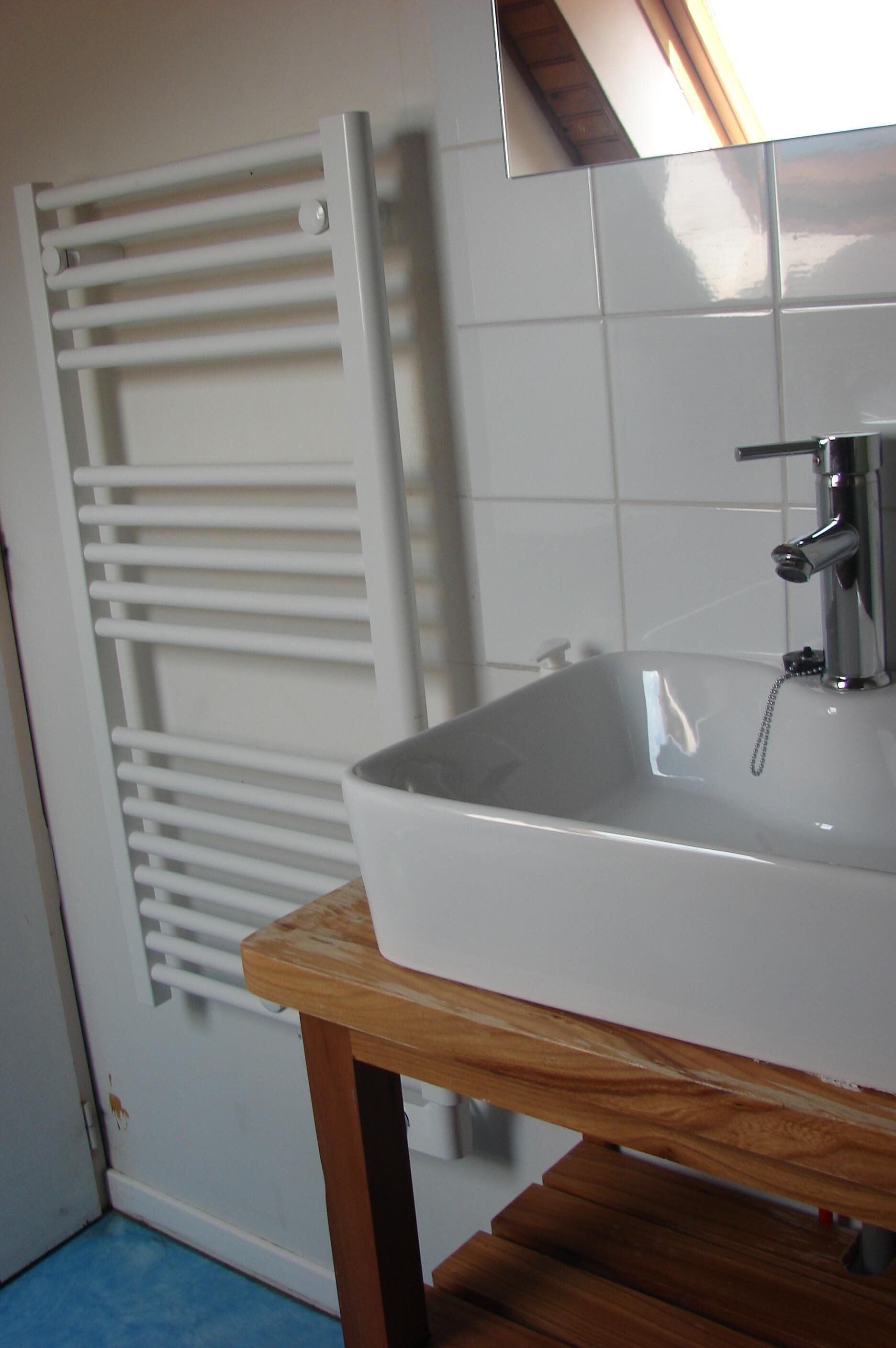 A bathroom with a white sink, wooden bench, and a white towel rack.