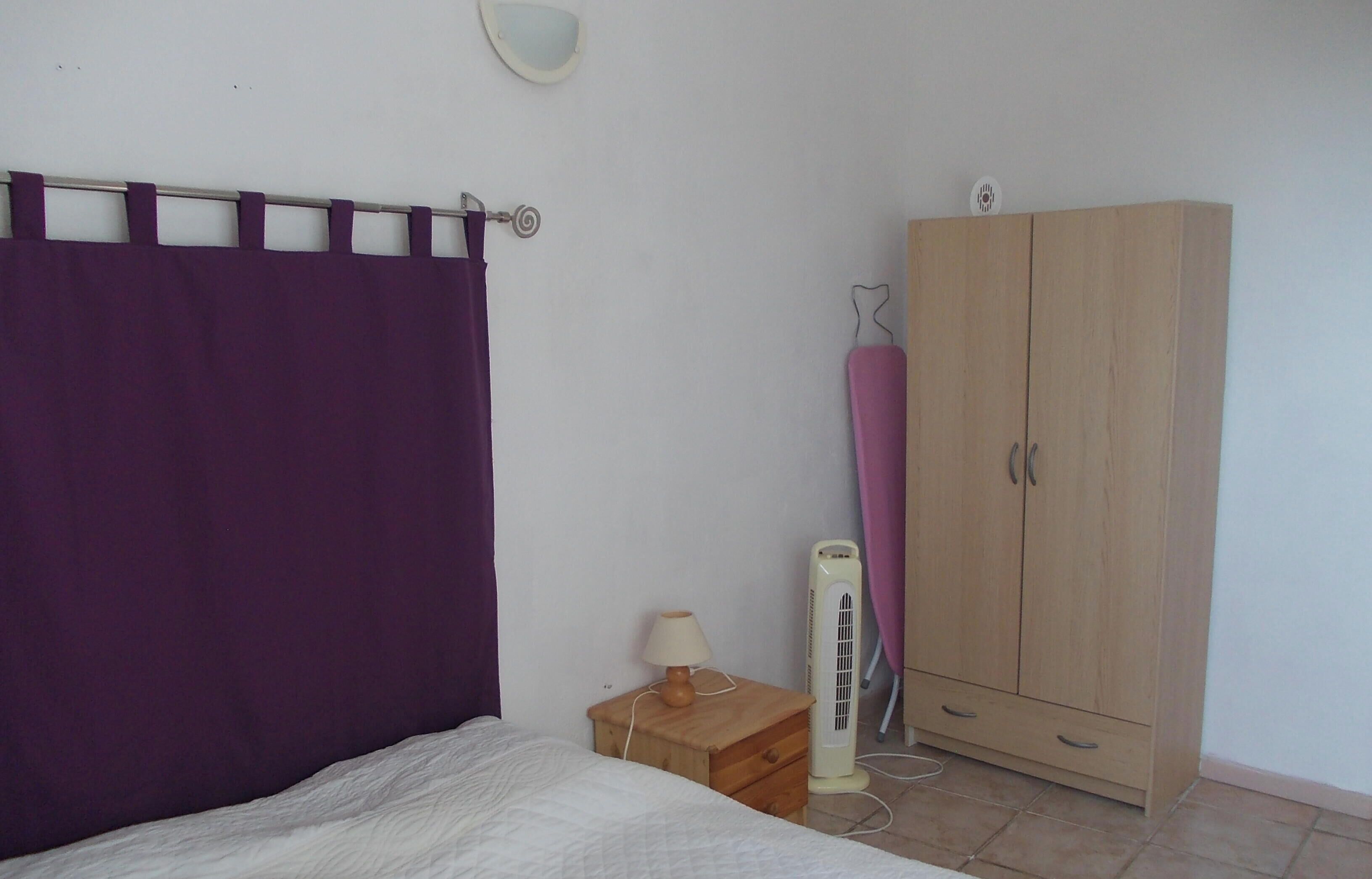 Un dormitorio con cama, armario, calefacción y cortina.