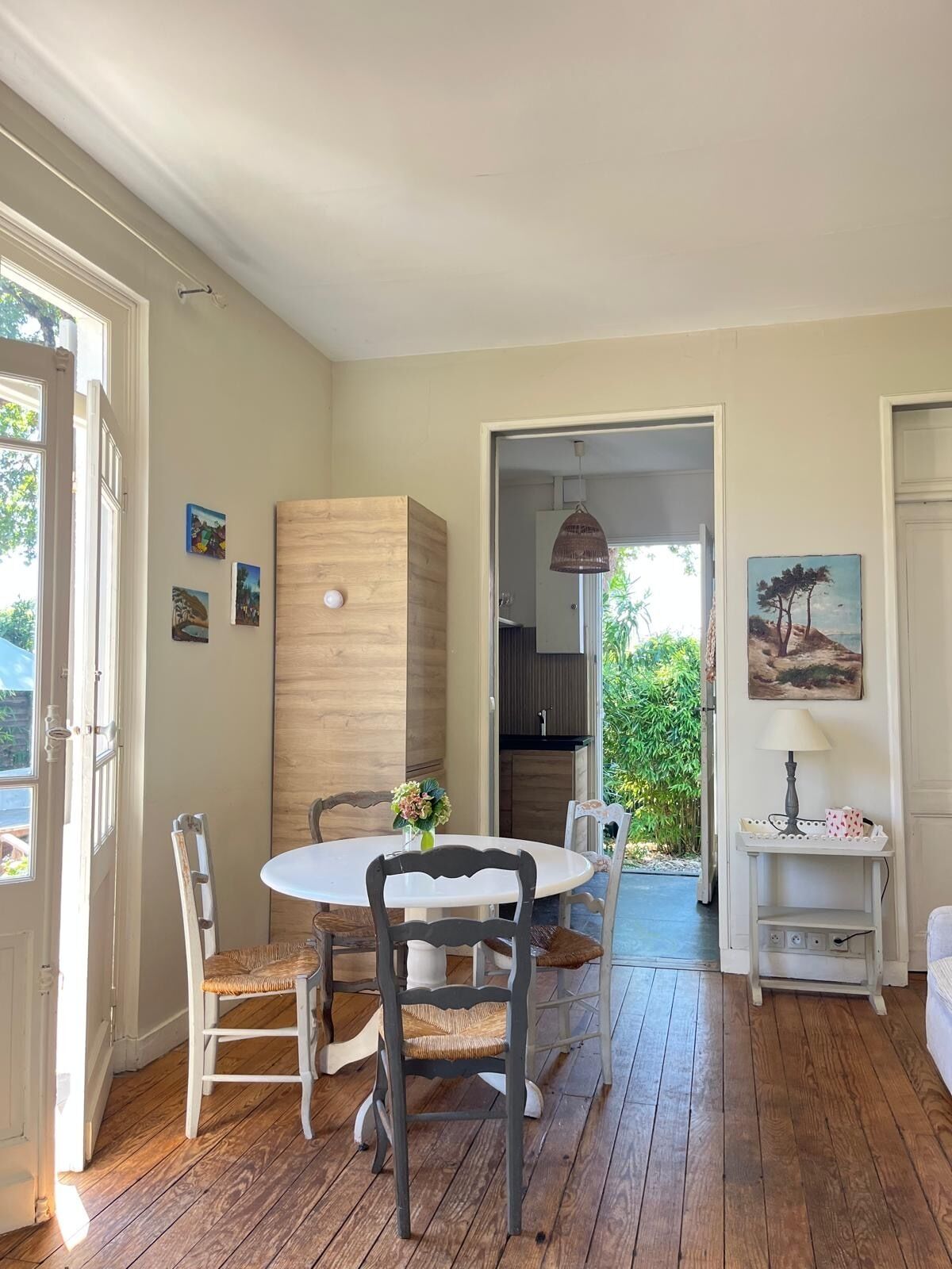 Uma sala de jantar com uma mesa redonda e cadeiras, um armário de madeira e um quadro na parede.