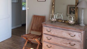 Una habitación con un aparador de madera, una silla, un espejo e impresión botánica enmarcada en la pared.