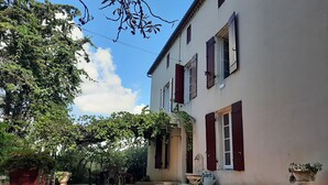 A building with a paved courtyard, potted plants, and a clear sky. - old farmhouse renovated (Aiguillon)