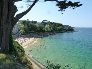 A coastal beach with clear waters, a sandy shore, and buildings along the cliffside. - SEA BRIGHT (Douarnenez)