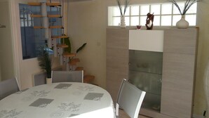 Un salon moderne comprenant un coin repas, une cheminée intégrée et un escalier menant à un niveau supérieur.