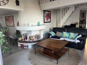 Ein Wohnzimmer mit Kamin, einem schwarzen Ledersofa und einem Couchtisch.