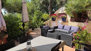 An outdoor patio with wicker furniture, a table, and a water bottle. - House in Grimaud with exceptional views of the sea and the Gulf of Saint-Tropez (GRIMAUD)
