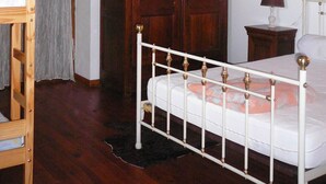 Um quarto com estrutura de cama de madeira, guarda-roupa de madeira e uma pequena mesa de cabeceira com uma luminária.