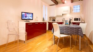 A modern kitchen with wooden beams, a dining table with chairs, a TV, and a microwave.