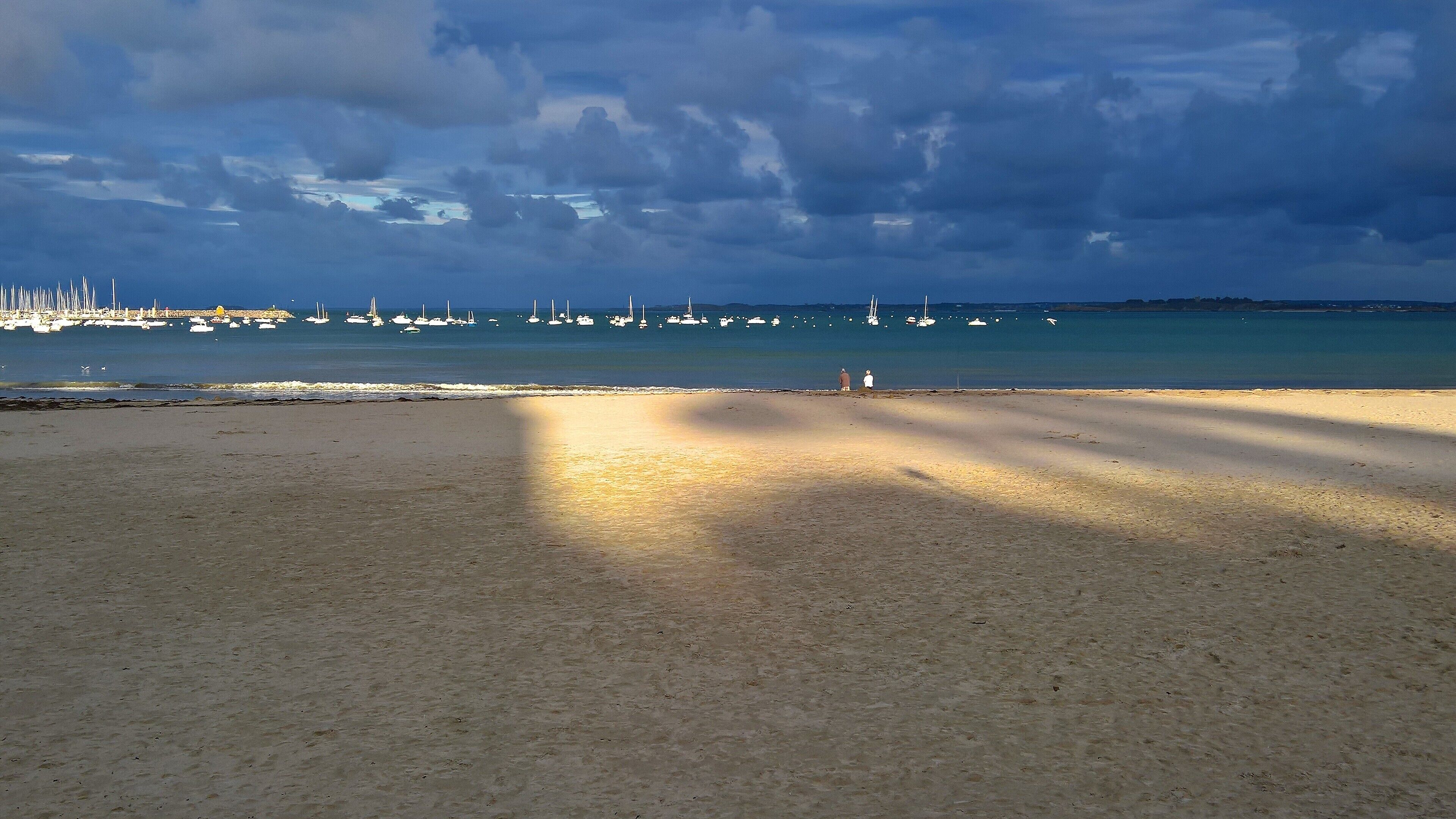 Ein Strand mit sandigem Ufer und Booten im Wasser.