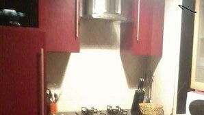 Une cuisine avec des meubles de rangement rouges, une cuisinière à gaz et un four à micro-ondes.