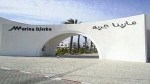 Une entrée moderne avec une arche blanche et une signalétique multilingue, notamment en arabe.