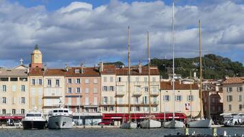 Un port avec des bateaux, une tour de l’horloge et des bâtiments dotés de balcons.