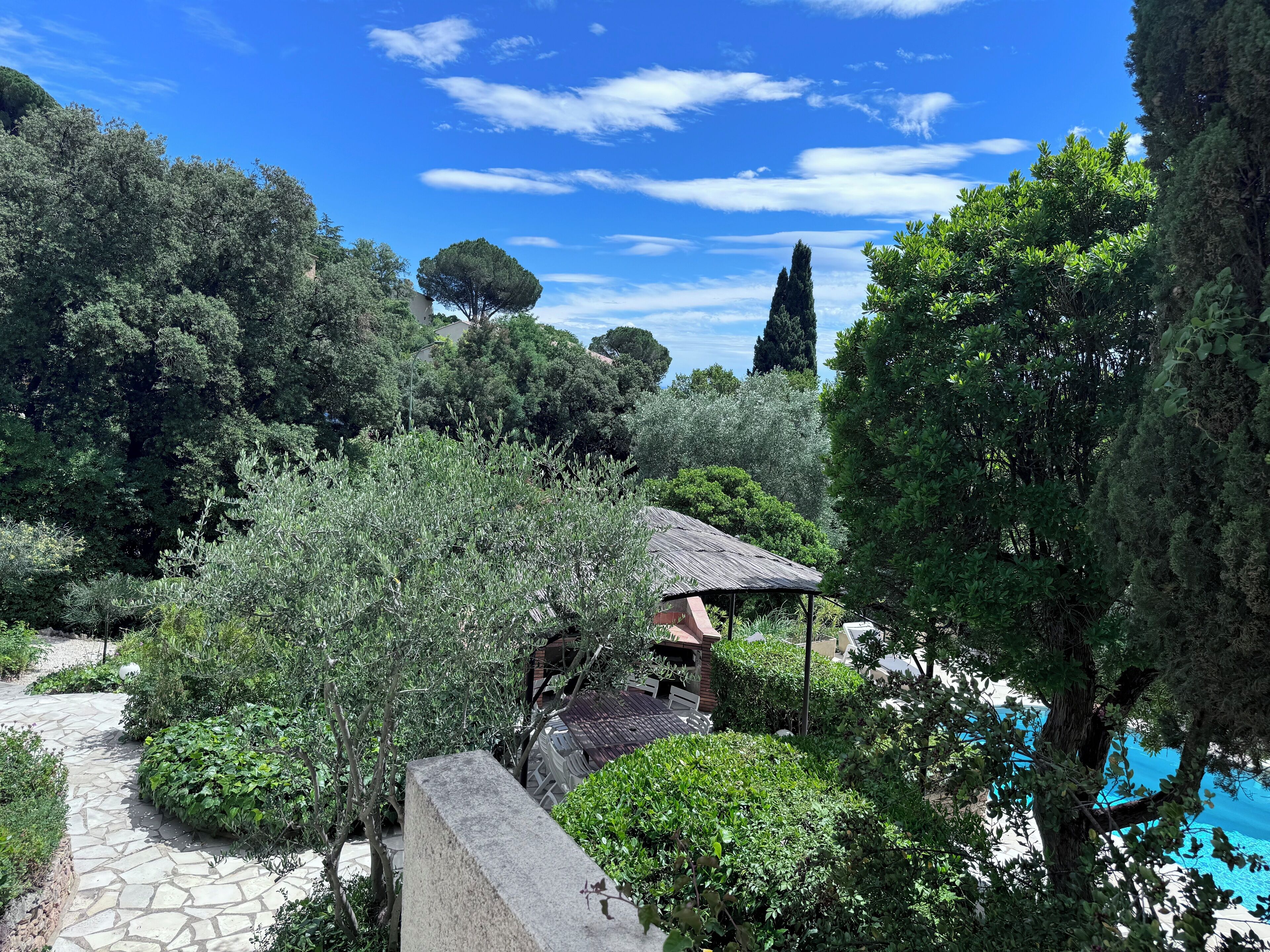 Un jardin avec un chemin de pierres, un kiosque rustique et un espace piscine.