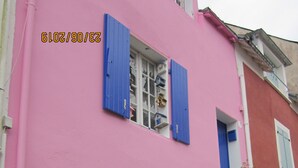 A pink building with blue shutters, a stone wall, and green plants. - PROMO CAUSE DESISTEMENT ... SMALL HOUSE OF FISHERMAN IN BEAUTIFUL ISLAND IN SEA (Le Palais)