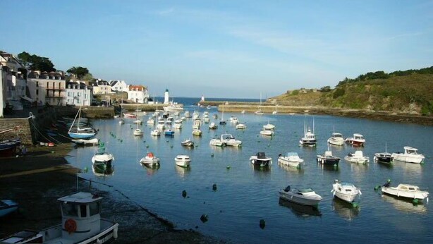 A harbor with numerous boats docked, a lighthouse in the distance, and buildings along the waterfront. - PROMO CAUSE DESISTEMENT ... SMALL HOUSE OF FISHERMAN IN BEAUTIFUL ISLAND IN SEA (Le Palais)
