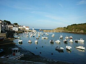 A harbor with numerous boats docked, a lighthouse in the distance, and buildings along the waterfront. - PROMO CAUSE DESISTEMENT ... SMALL HOUSE OF FISHERMAN IN BEAUTIFUL ISLAND IN SEA (Le Palais)