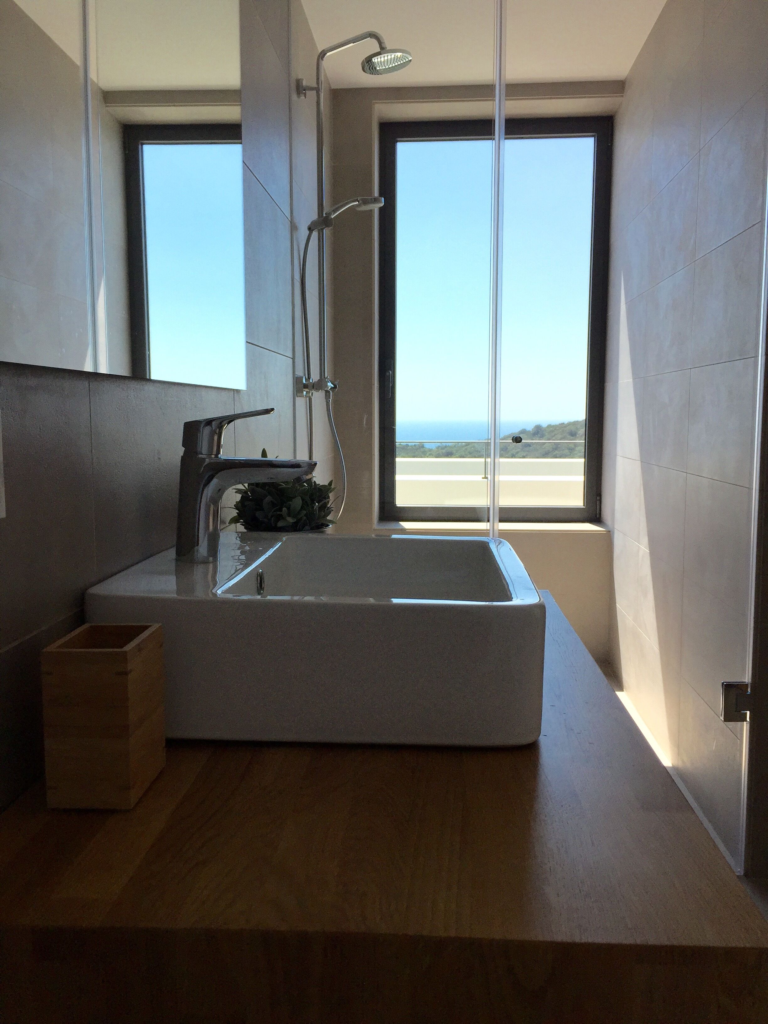 Casa de banho moderna com uma janela grande, lavatório embutido e chuveiro.
