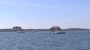 A waterfront property with two buildings on stilts, boats on the water, and a clear sky.