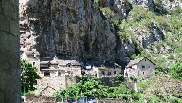 Un bâtiment en pierre, avec une falaise rocheuse abrupte en arrière-plan.