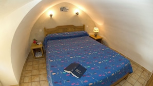 Une chambre à coucher avec un lit, une table de chevet, une lampe et une petite table sur laquelle se trouve un livre.