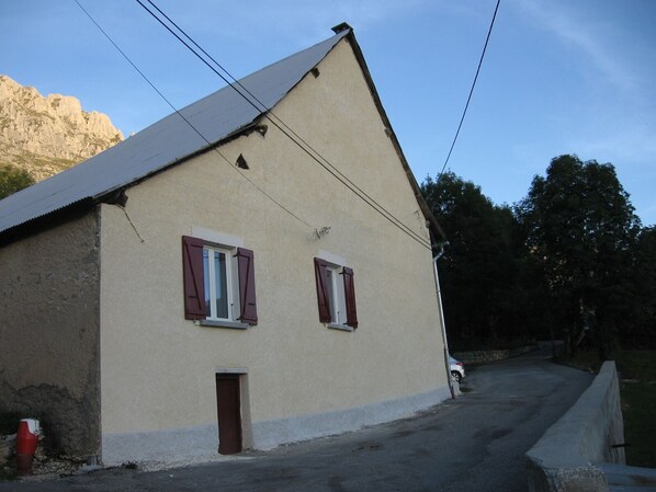 A two-story building with a sloped roof, two windows with shutters, and a small door. - House near the ski slopes, 4 people, fully equipped (Dévoluy)