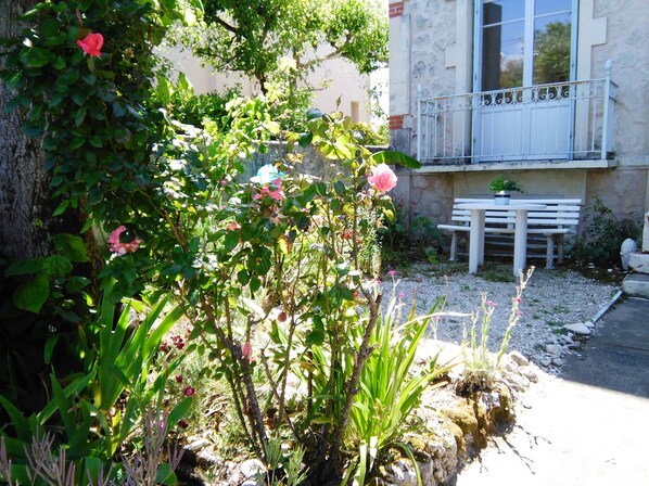A garden with rose bushes, a white bench, and a stone wall.