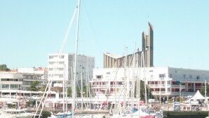 A marina with multiple boats docked, a building with a modern design, and a clear blue sky. - PIGEONNIER BEACH 5 'ON FOOT; BEACH DE PONTAILLAC 8 'all on foot (Royan)