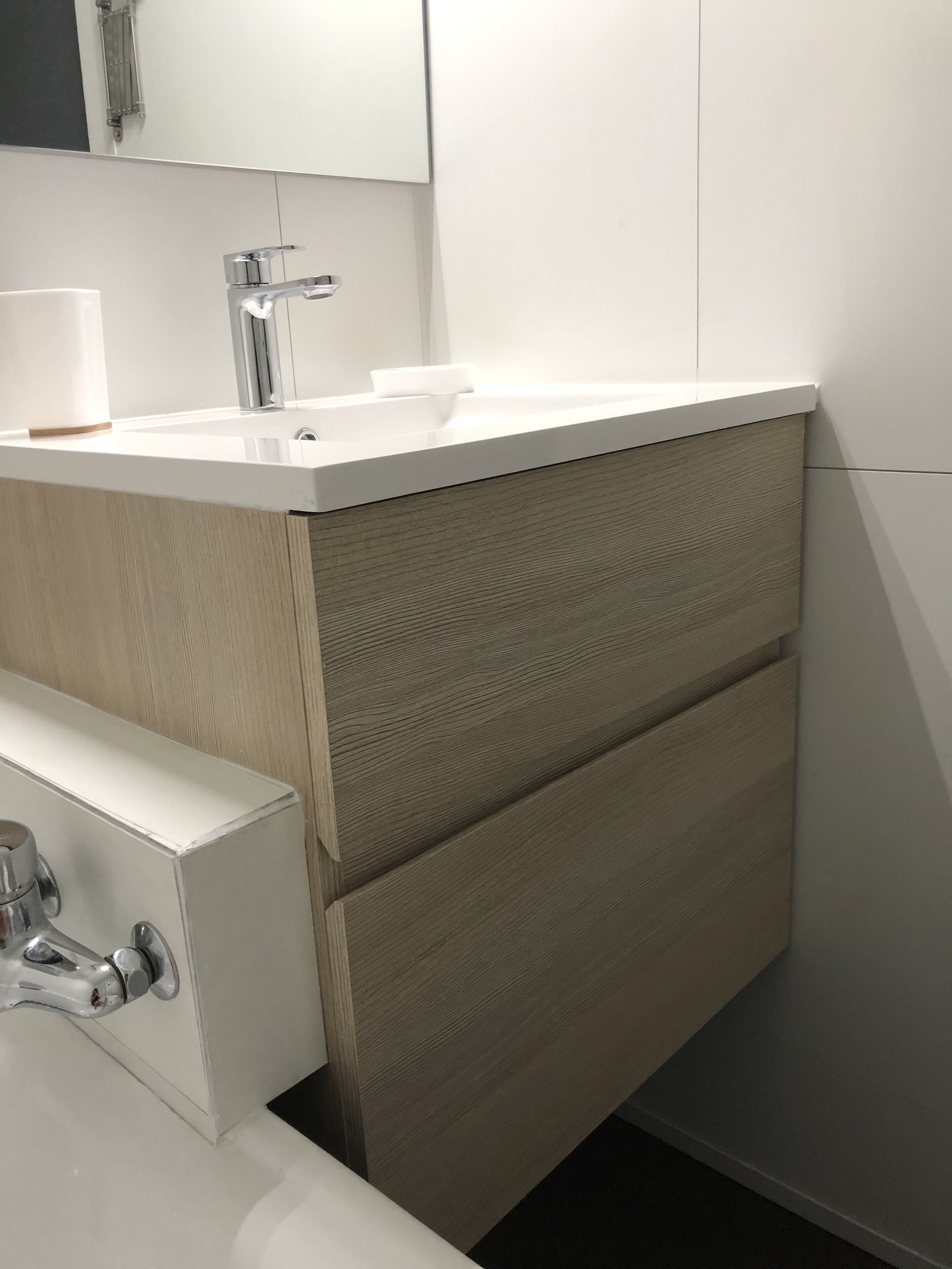 Un baño moderno con tocador blanco, espejo y lavamanos.