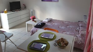 A bedroom with a bed, a desk, a chair, a television, and a window. - CALM STUDIO IN A GREEN SETTING (Montauban)
