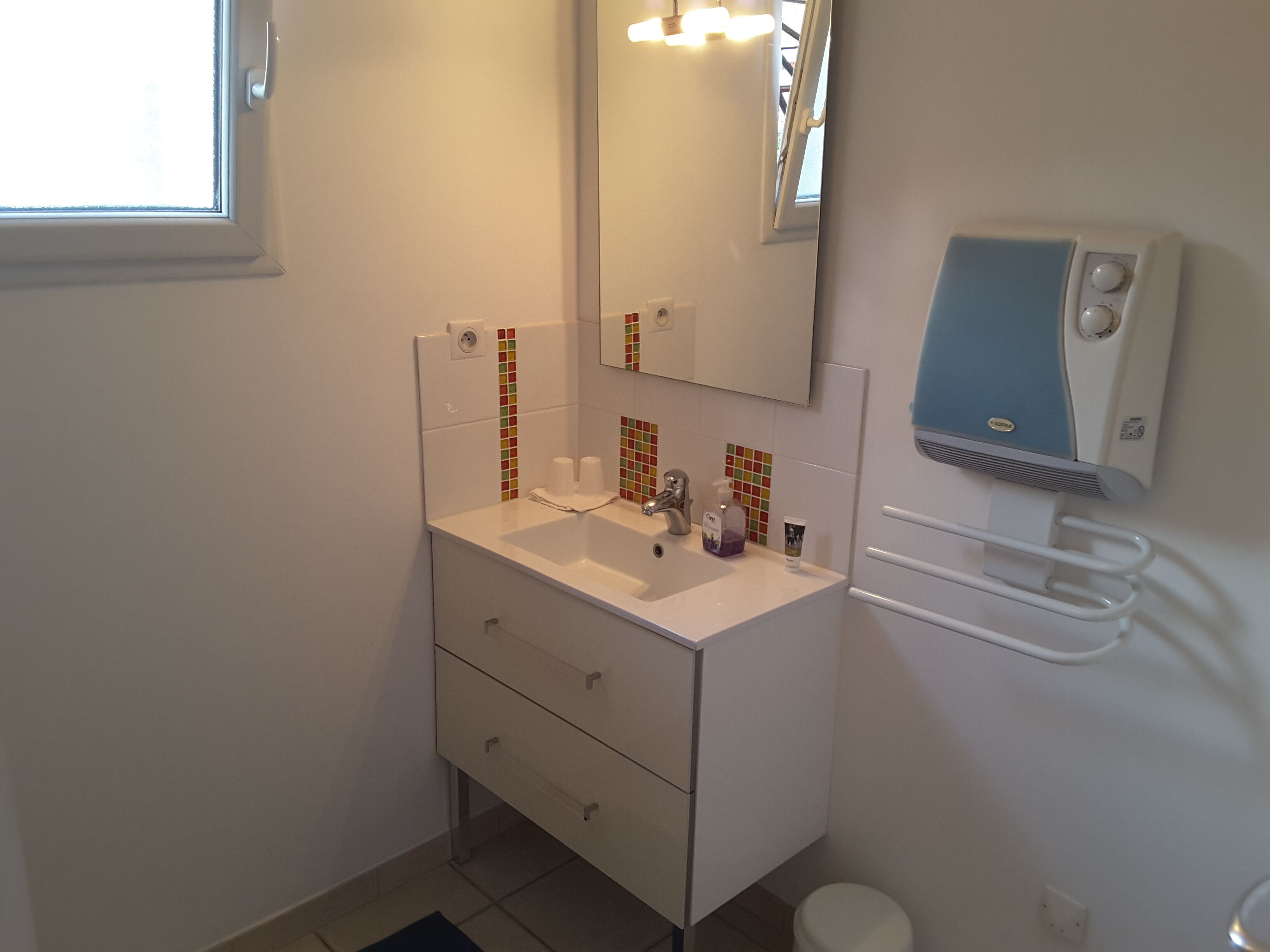 Een badkamer met een witte wastafel, spiegel en handdoekhouder.