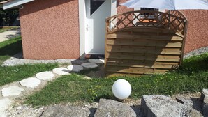 A small building with a white door, a wooden gate, and a white umbrella. - CALM STUDIO IN A GREEN SETTING (Montauban)