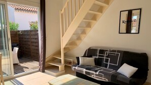 Een woonkamer met een bank, salontafel en een trap naar een hoger gelegen verdieping.